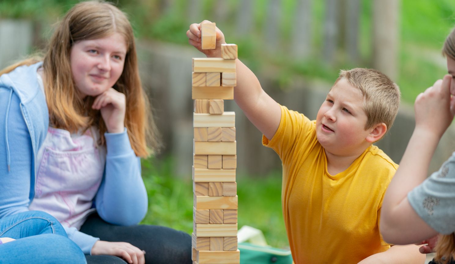 children and adult playing with jenga