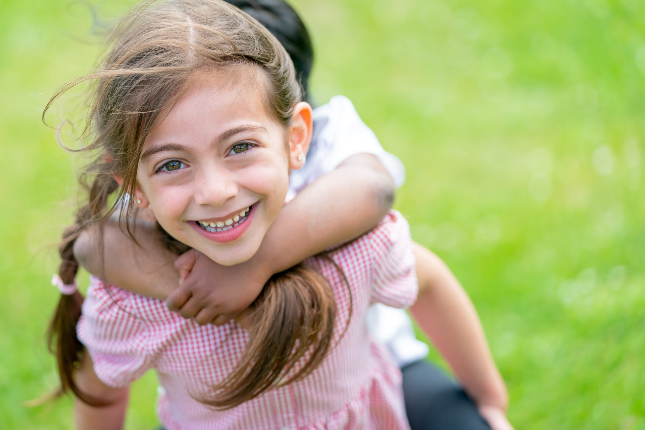 smiling girl in playing field with friends hand around neck